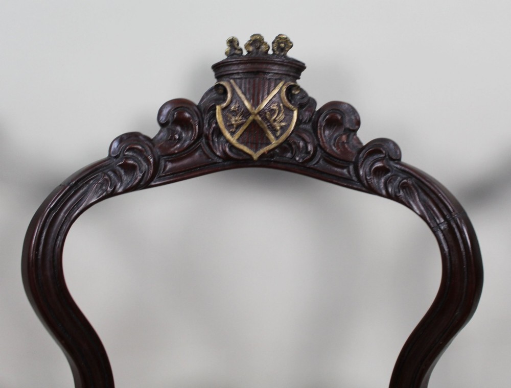 A set of four mid-Victorian dark mahogany side chairs featuring open-carved balloon backs topped with heraldic crest shields and cabriole front legs. View XI