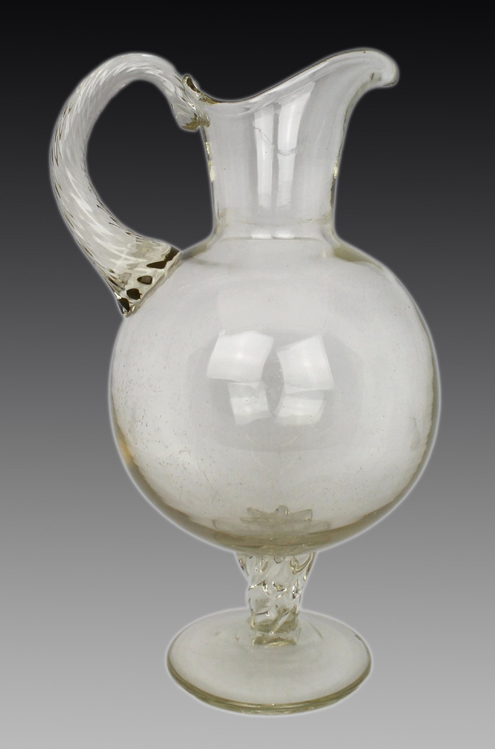 A late 19th-century Italian hand-blown clear glass footed ewer featuring a spherical body, pinched spout, applied ribbed handle, and twisted stem on a flat circular base.