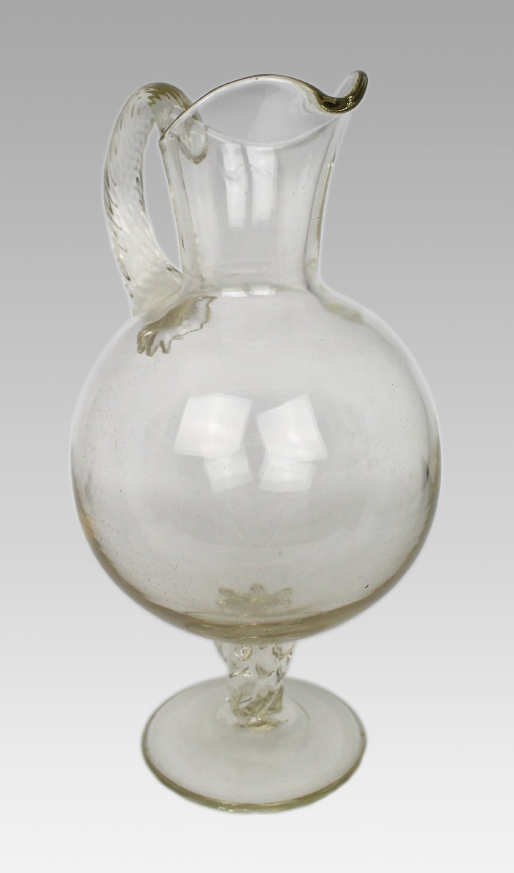A late 19th-century Italian hand-blown clear glass footed ewer featuring a spherical body, pinched spout, applied ribbed handle, and twisted stem on a flat circular base. View II