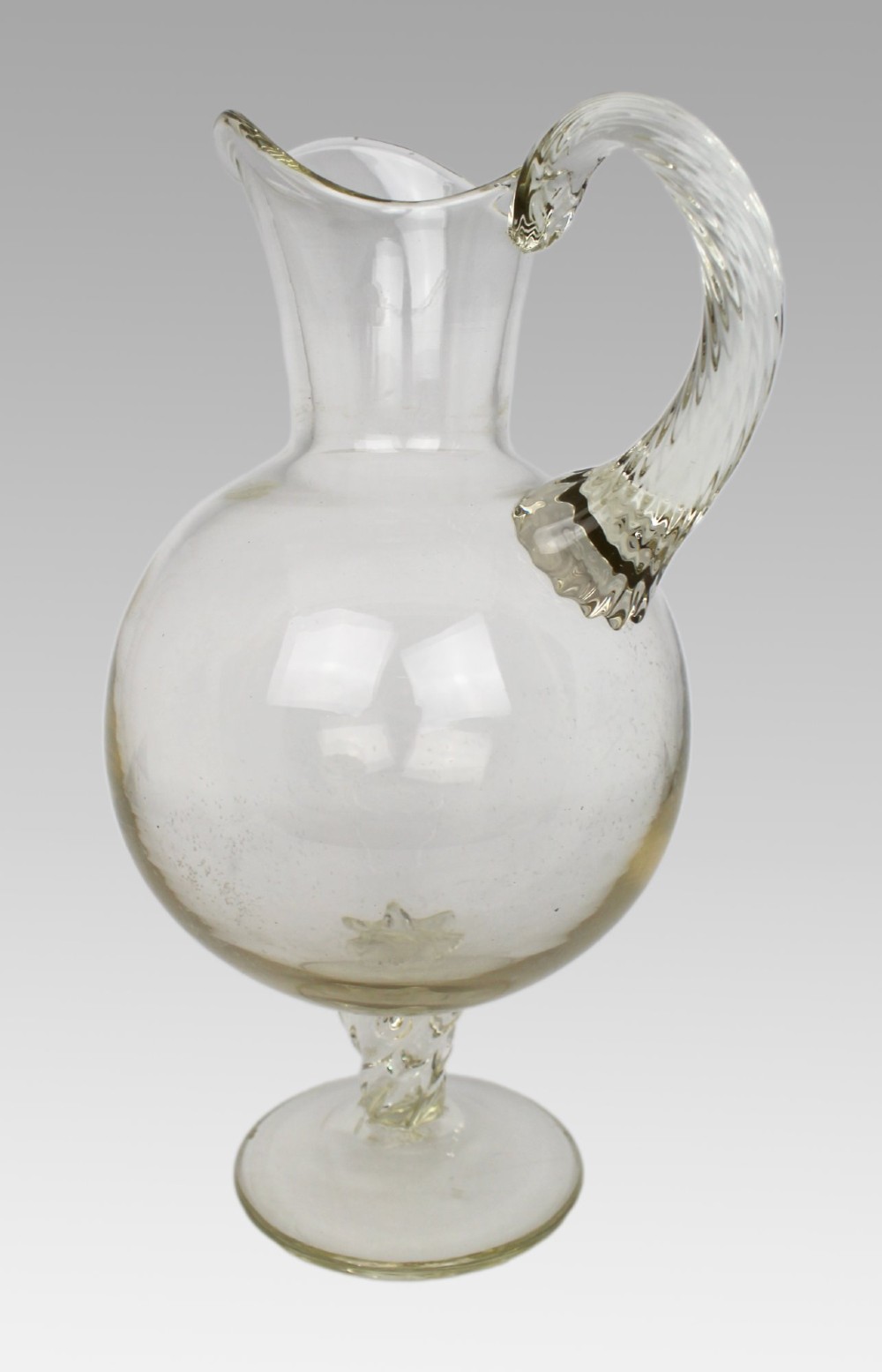 A late 19th-century Italian hand-blown clear glass footed ewer featuring a spherical body, pinched spout, applied ribbed handle, and twisted stem on a flat circular base. View III