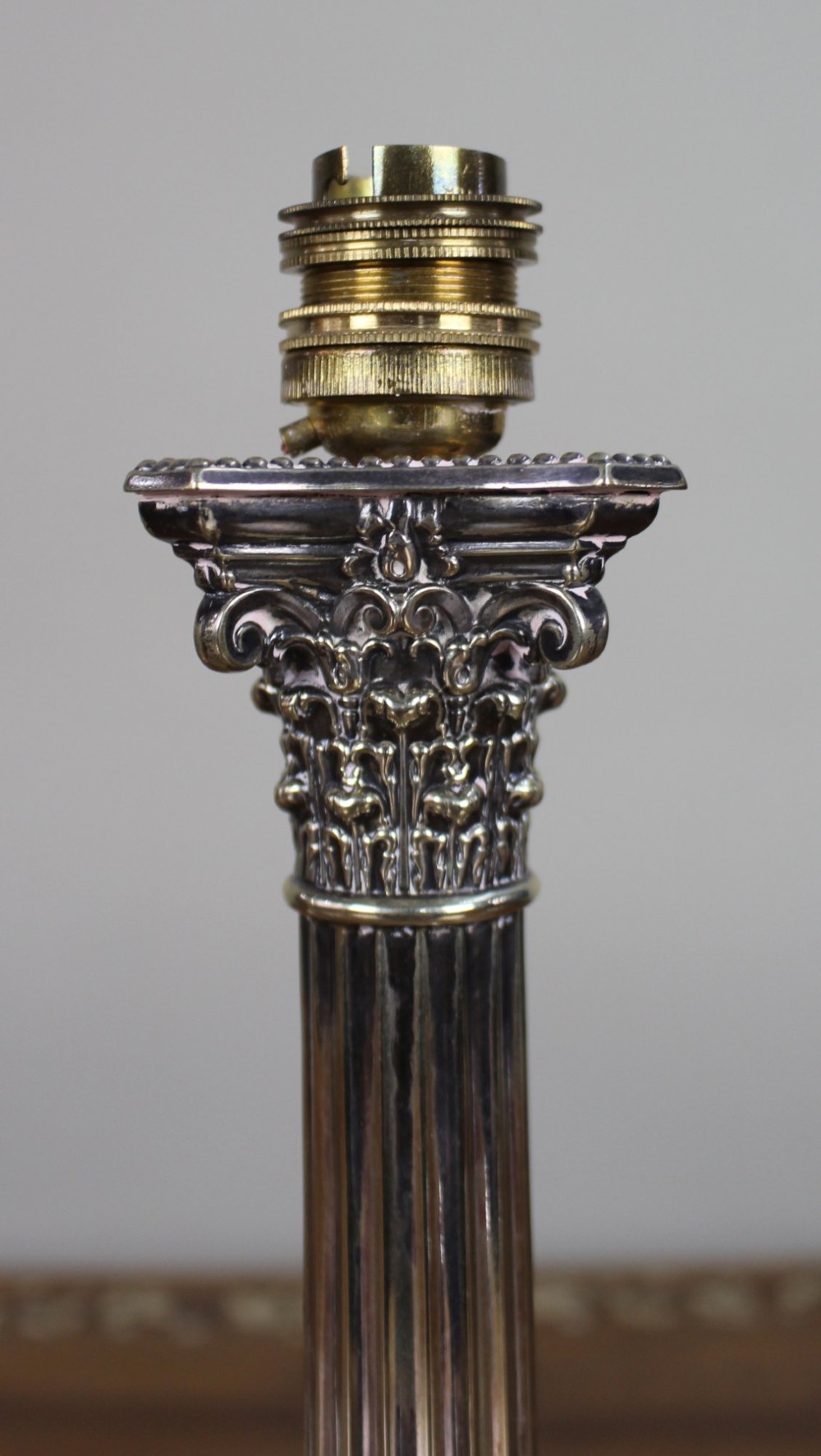 A silver-plated table lamp featuring a fluted Corinthian column shaft, a stepped square base, and a cream pleated fabric shade. View VII