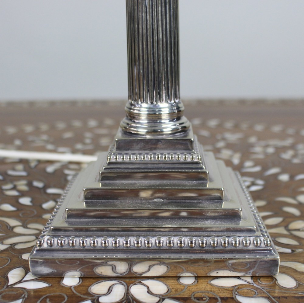 A silver-plated table lamp featuring a fluted Corinthian column shaft, a stepped square base, and a cream pleated fabric shade. View IX