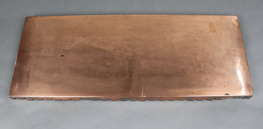 A rectangular Georgian copper hearth plate featuring a scalloped lower edge and a polished metallic surface. View II