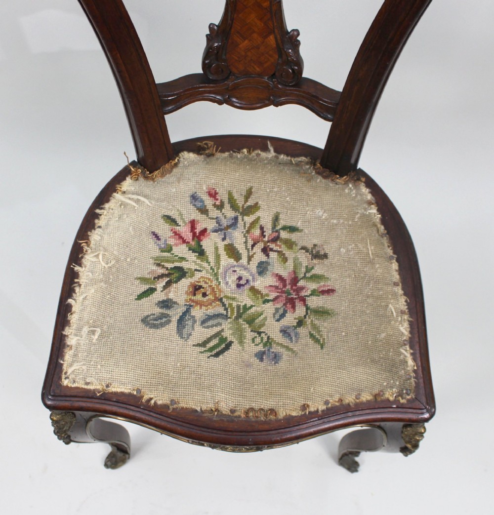 An antique French side chair featuring a kingwood back frame with a parquetry splat, cabriole front legs decorated with ormolu mounts, and a floral needlepoint seat. View VI