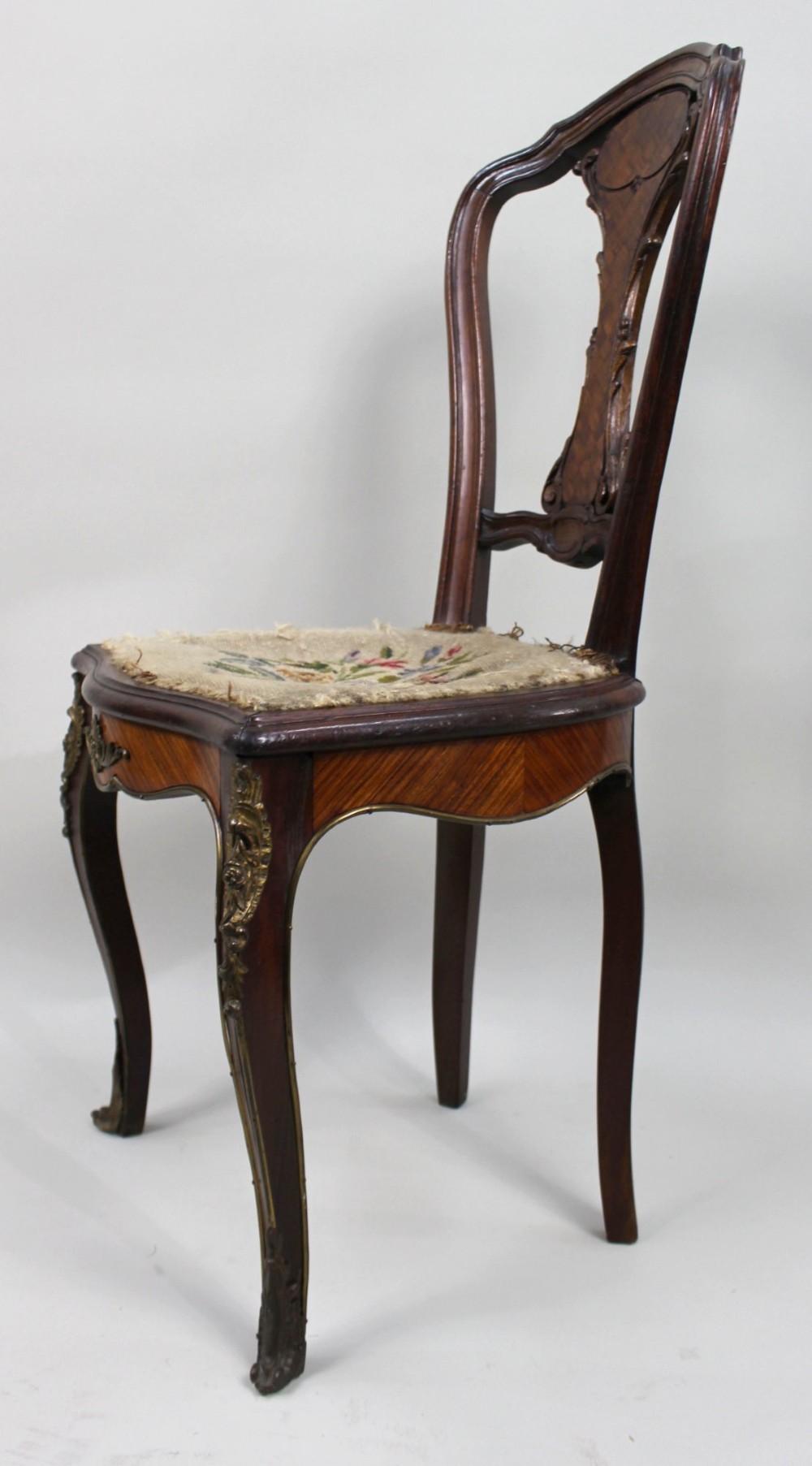 An antique French side chair featuring a kingwood back frame with a parquetry splat, cabriole front legs decorated with ormolu mounts, and a floral needlepoint seat. View VII