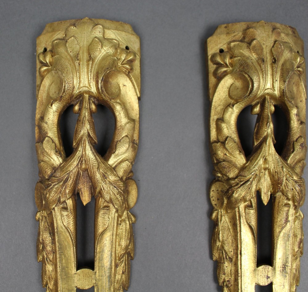 A pair of ornate gilt bronze furniture mounts featuring acanthus leaf scrollwork and symmetrical pierced design in the Louis XVI style. View II