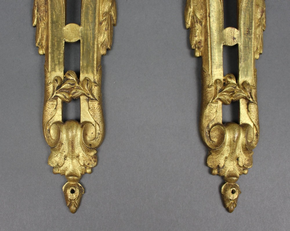 A pair of ornate gilt bronze furniture mounts featuring acanthus leaf scrollwork and symmetrical pierced design in the Louis XVI style. View III