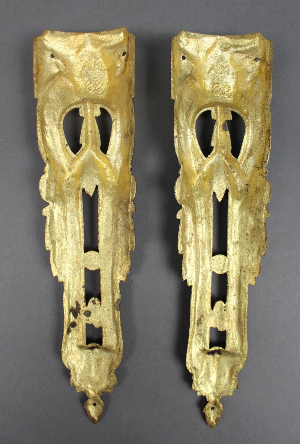 A pair of ornate gilt bronze furniture mounts featuring acanthus leaf scrollwork and symmetrical pierced design in the Louis XVI style. View IV