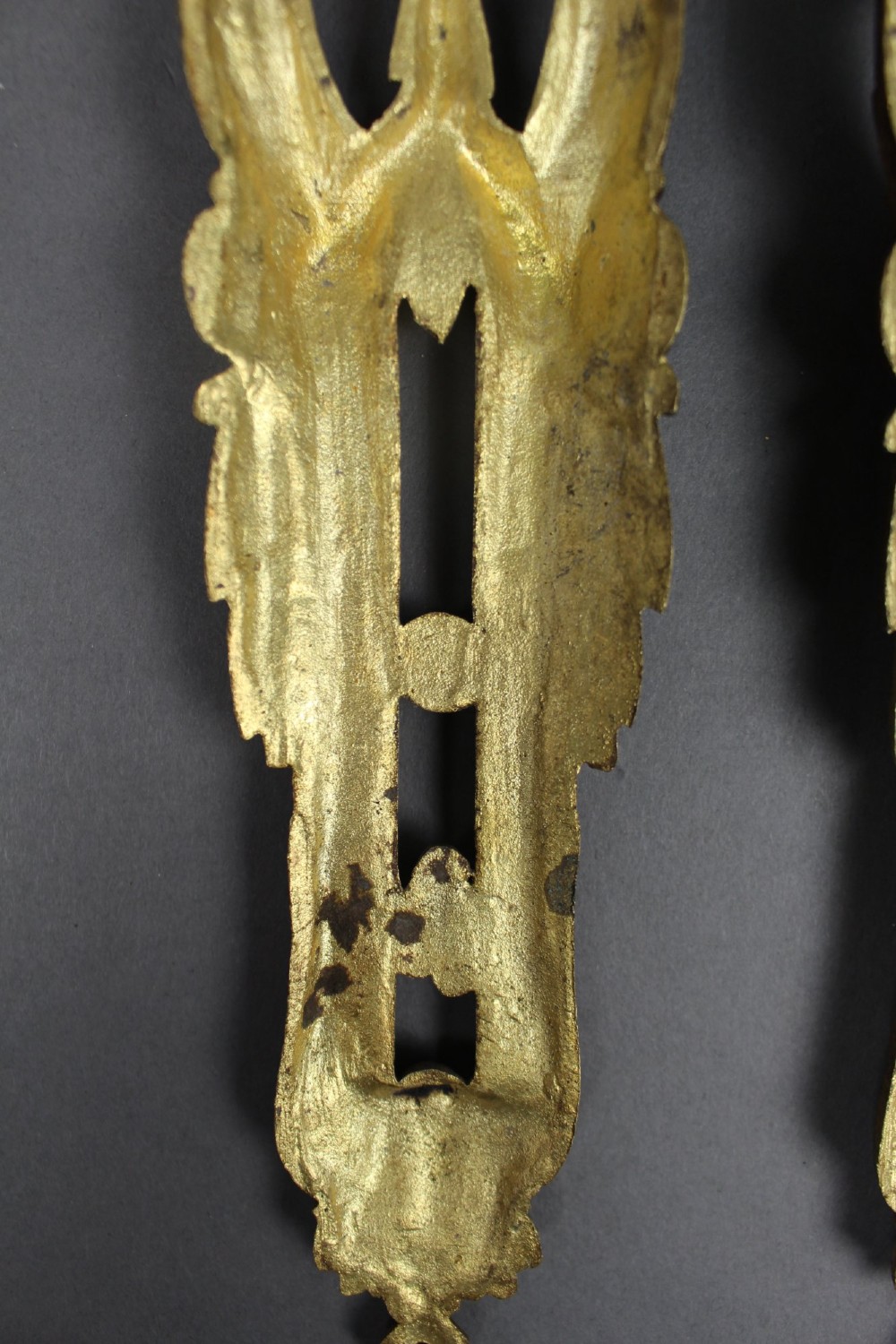 A pair of ornate gilt bronze furniture mounts featuring acanthus leaf scrollwork and symmetrical pierced design in the Louis XVI style. View VI