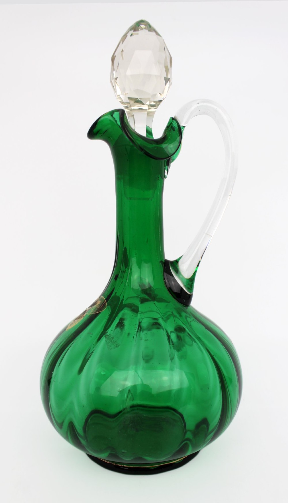 An emerald green glass claret jug featuring a ribbed bulbous body decorated with hand-painted gold floral motifs, a clear looped handle, and a faceted clear glass stopper. View III
