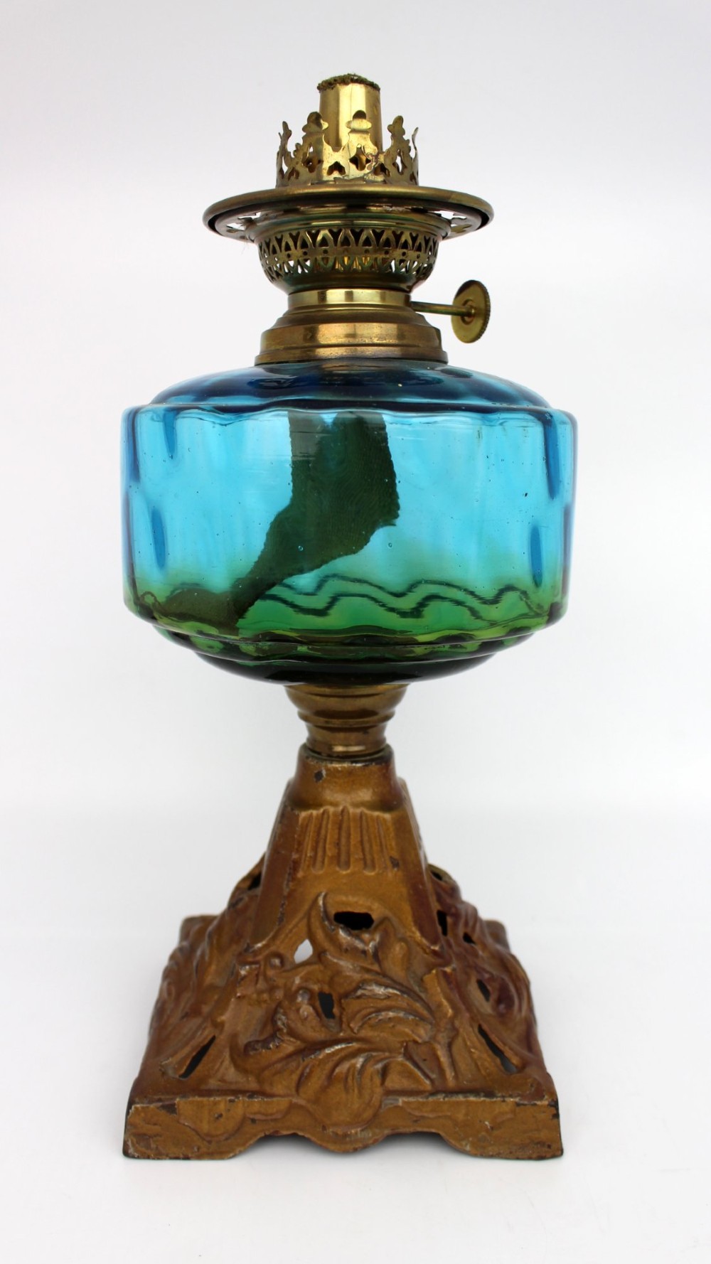 An antique Victorian oil lamp featuring a cast metal base with scrolling leaf motifs, a vibrant blue glass font, and a brass burner gallery. View VIII