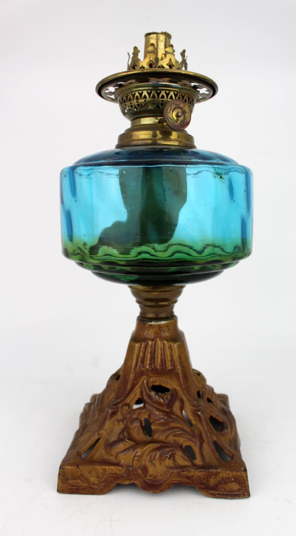 An antique Victorian oil lamp featuring a cast metal base with scrolling leaf motifs, a vibrant blue glass font, and a brass burner gallery. View IX
