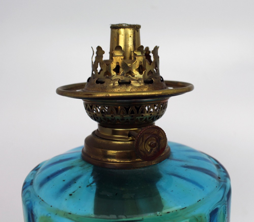 An antique Victorian oil lamp featuring a cast metal base with scrolling leaf motifs, a vibrant blue glass font, and a brass burner gallery. View XI