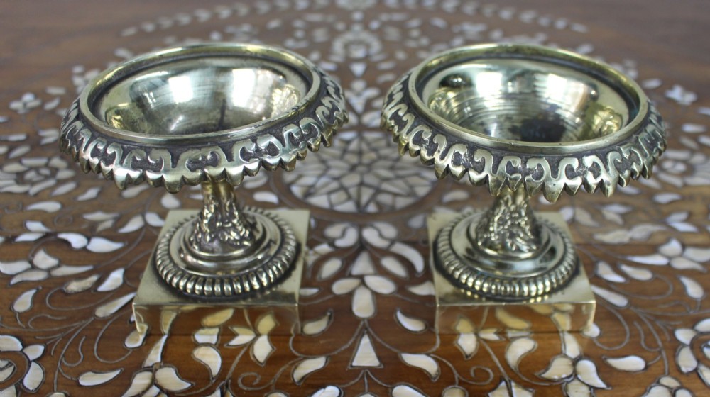 A pair of small antique bronze and brass urns featuring scalloped rims, relief scrollwork, and flared pedestals on square bases. View III