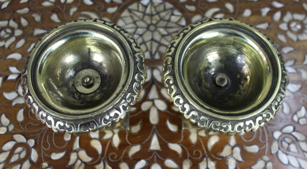 A pair of small antique bronze and brass urns featuring scalloped rims, relief scrollwork, and flared pedestals on square bases. View IV