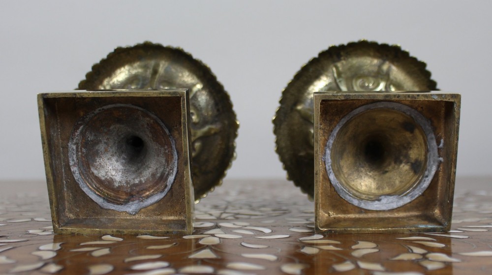 A pair of small antique bronze and brass urns featuring scalloped rims, relief scrollwork, and flared pedestals on square bases. View VI