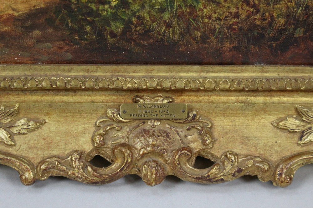 A 19th-century Victorian oil painting depicting figures outdoors feeding a kitten, enclosed within an elaborate carved gilt frame. View VI