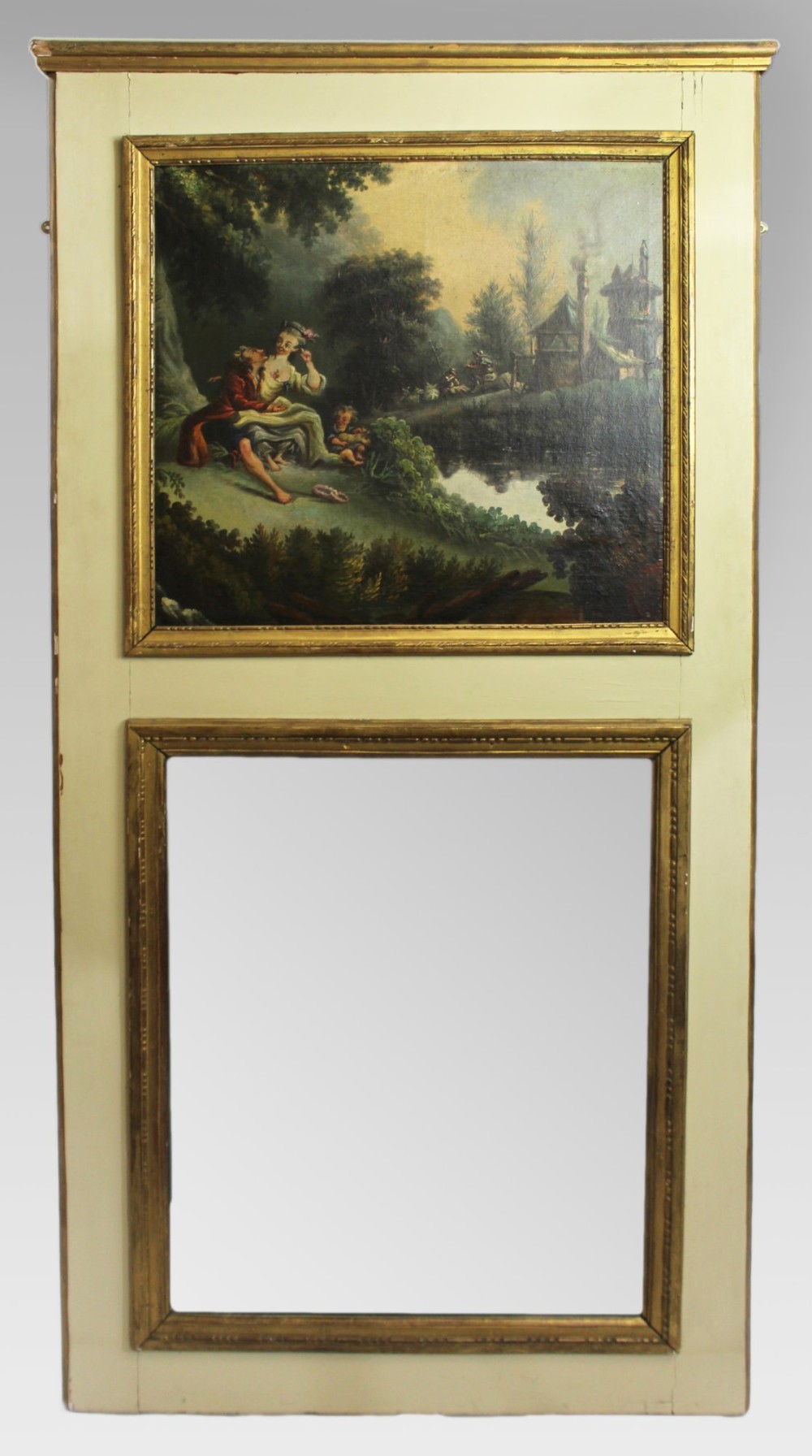 A tall cream-painted French trumeau wall mirror featuring an upper framed pastoral oil painting and a lower rectangular mirror glass set within gilded mouldings.