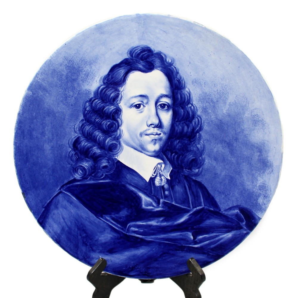 A circular glazed ceramic charger featuring a monochrome cobalt blue hand-painted portrait of a seventeenth-century man against a light blue background.