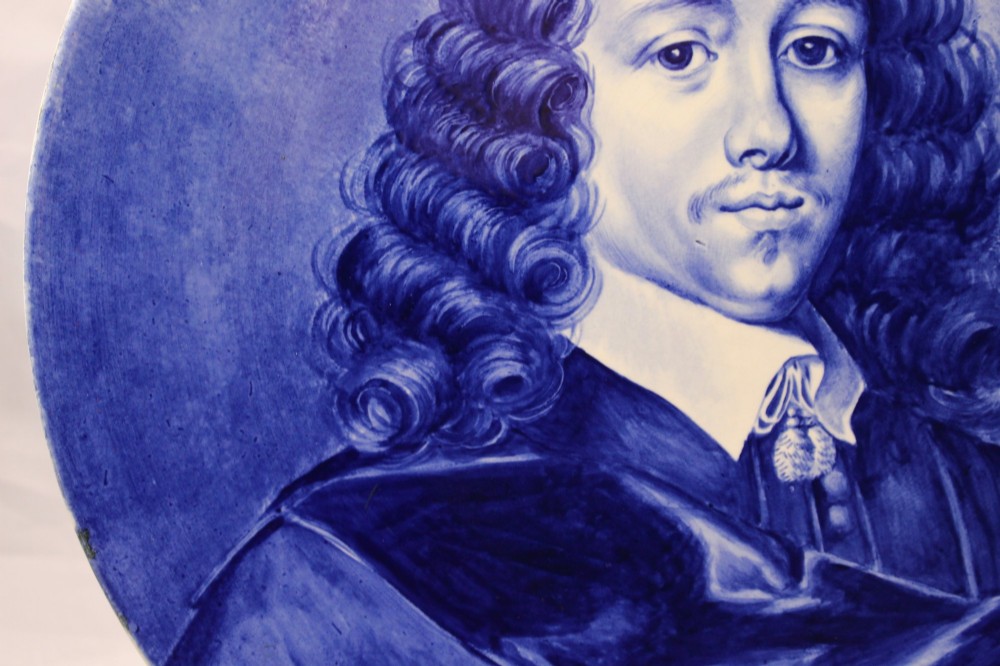 A circular glazed ceramic charger featuring a monochrome cobalt blue hand-painted portrait of a seventeenth-century man against a light blue background. View V