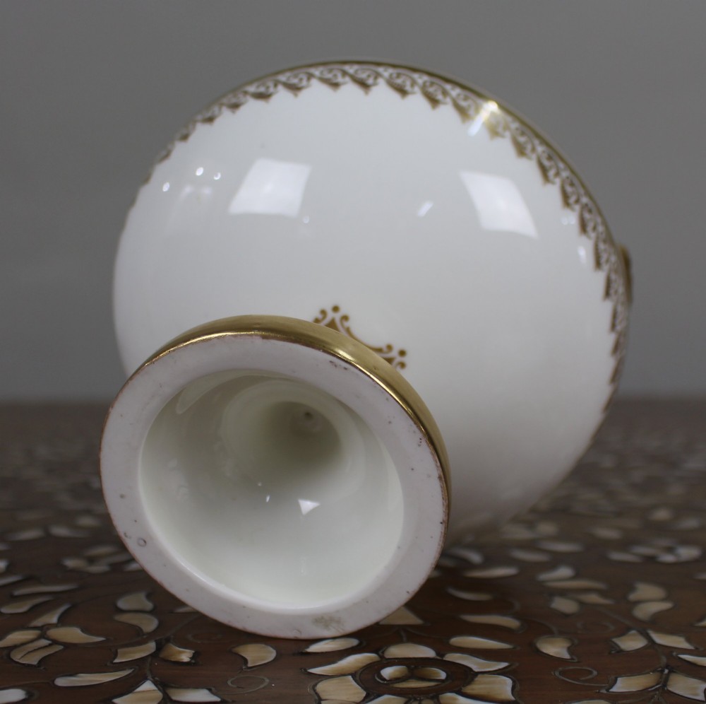 A 19th-century white porcelain urn featuring gilded side handles, a classical scroll frieze, and a fluted pedestal foot. View VIII