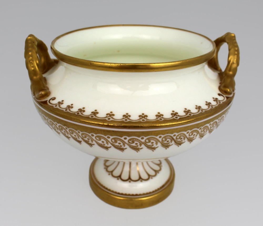 A 19th-century white porcelain urn featuring gilded side handles, a classical scroll frieze, and a fluted pedestal foot. View XII