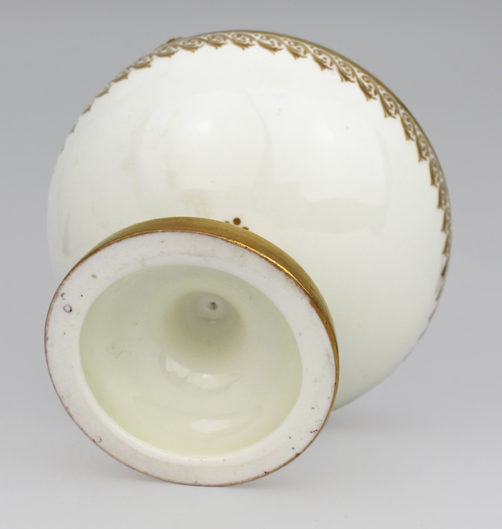 A 19th-century white porcelain urn featuring gilded side handles, a classical scroll frieze, and a fluted pedestal foot. View XV