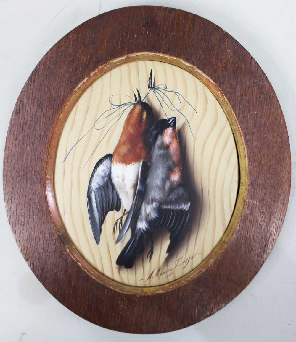 An oval oil painting on a wood panel depicting two hanging songbirds painted in trompe loeil style inside a wide wooden frame. View III