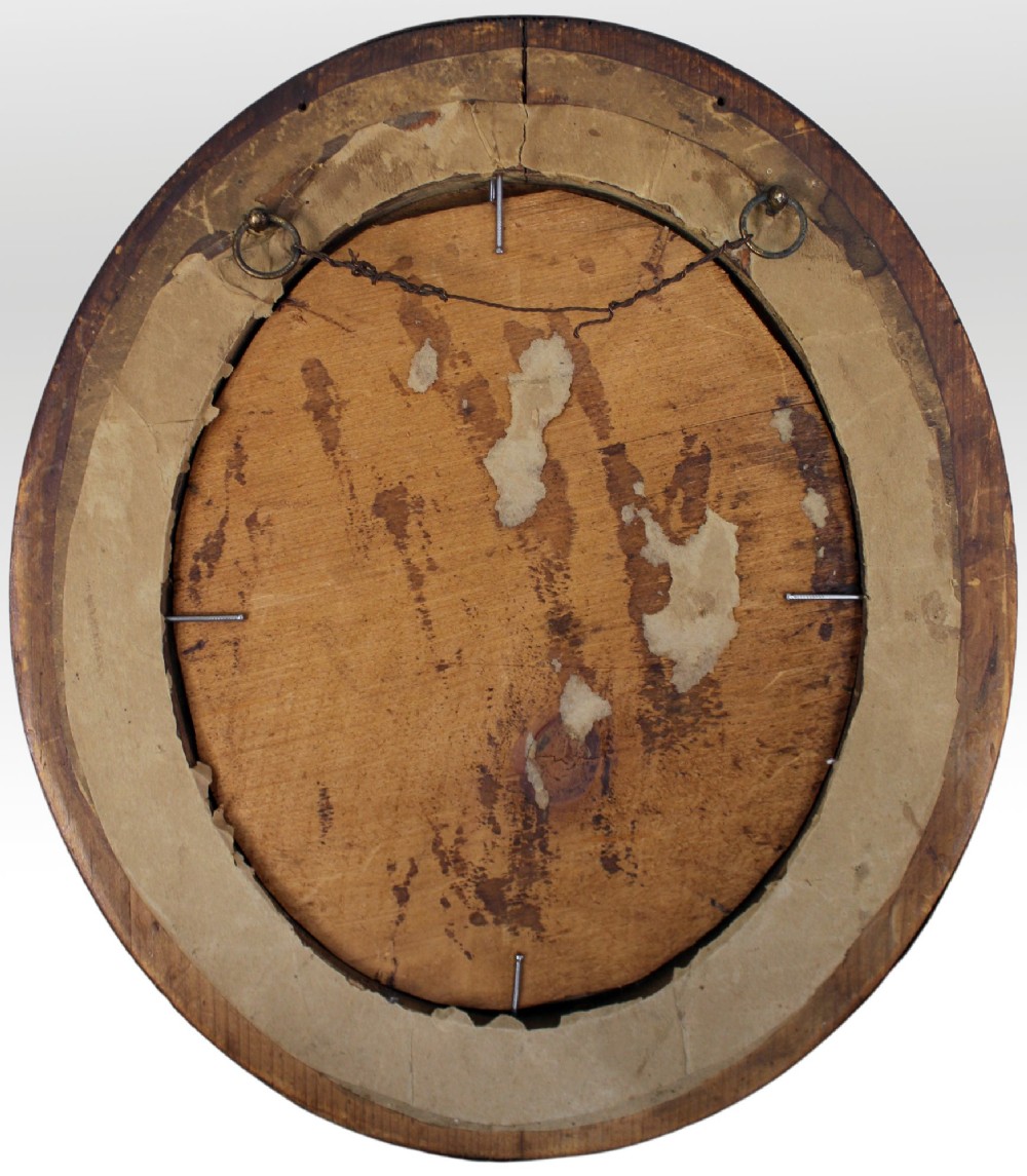 An oval oil painting on a wood panel depicting two hanging songbirds painted in trompe loeil style inside a wide wooden frame. View V