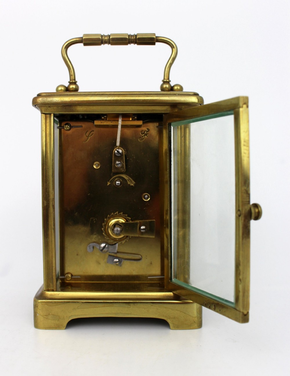 An antique brass carriage clock featuring rectangular glass side panels, a white enamel dial with black Roman numerals, and a folding top handle. View IV