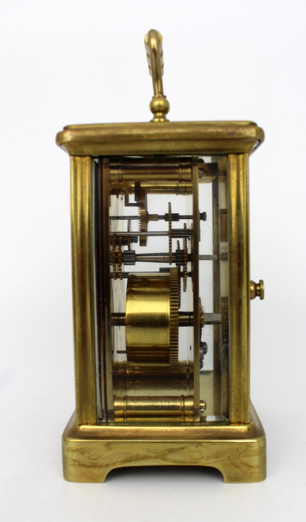 An antique brass carriage clock featuring rectangular glass side panels, a white enamel dial with black Roman numerals, and a folding top handle. View V