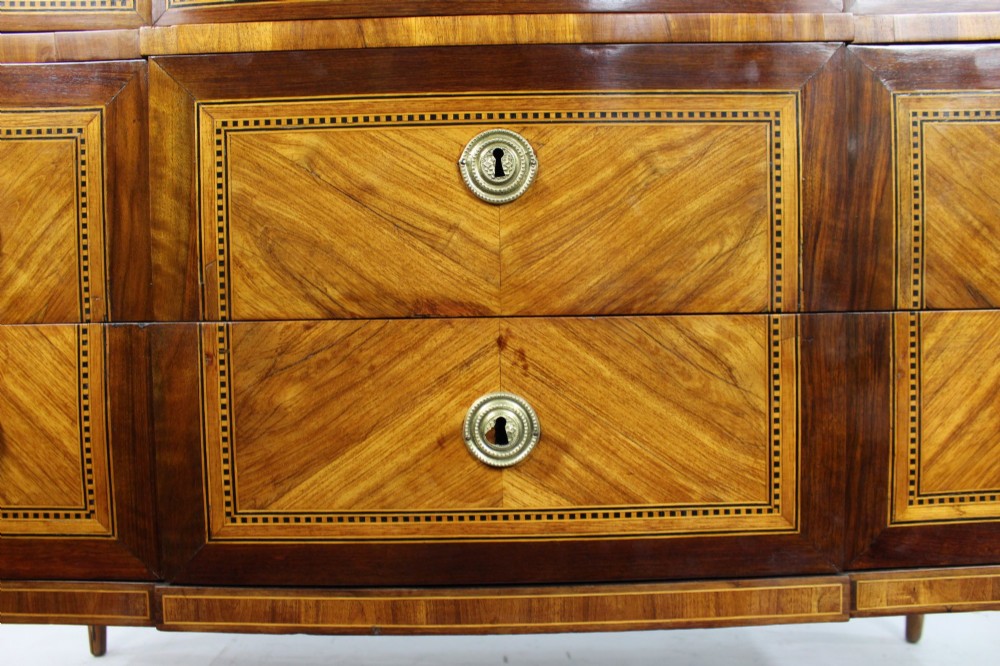 An 18th-century French Louis XVI commode featuring geometric parquetry wood inlay, tapered legs, brass ring handles, and a grey marble top. View VI