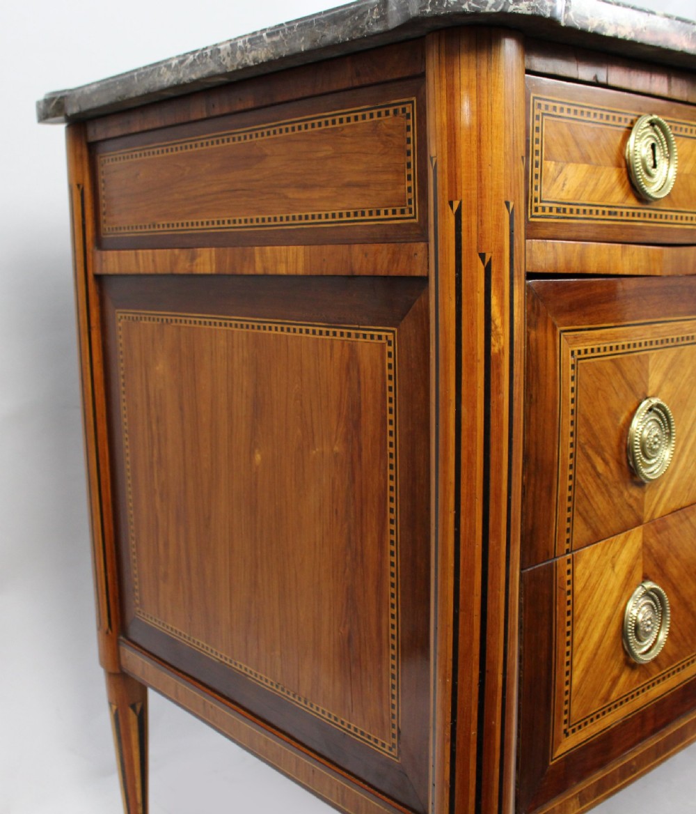 An 18th-century French Louis XVI commode featuring geometric parquetry wood inlay, tapered legs, brass ring handles, and a grey marble top. View VIII