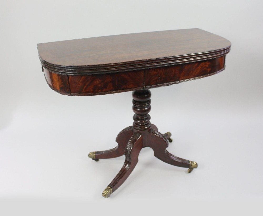An early nineteenth-century Regency mahogany tea table with a folded rounded top resting on a turned central column and four splayed legs with brass castors. View II