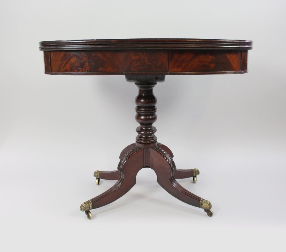 An early nineteenth-century Regency mahogany tea table with a folded rounded top resting on a turned central column and four splayed legs with brass castors. View III