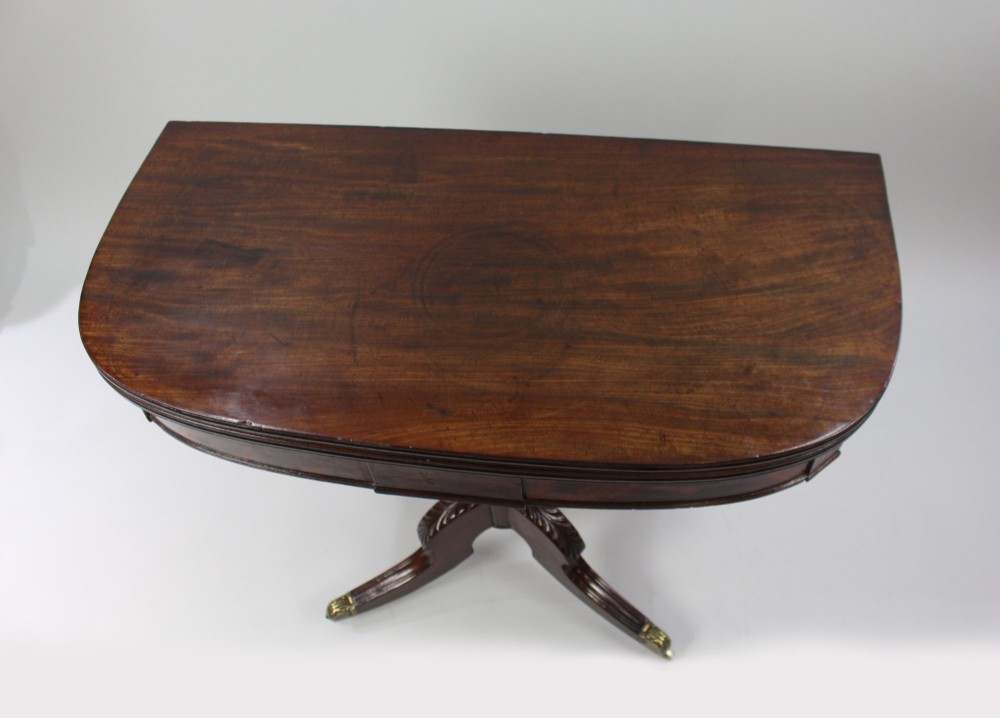 An early nineteenth-century Regency mahogany tea table with a folded rounded top resting on a turned central column and four splayed legs with brass castors. View IV