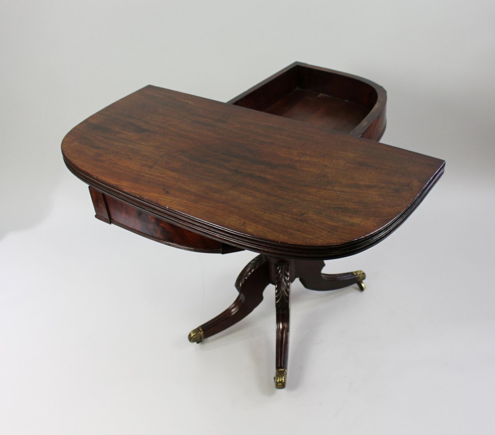 An early nineteenth-century Regency mahogany tea table with a folded rounded top resting on a turned central column and four splayed legs with brass castors. View V