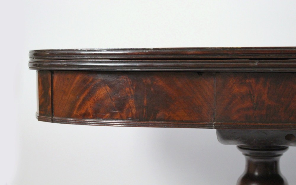 An early nineteenth-century Regency mahogany tea table with a folded rounded top resting on a turned central column and four splayed legs with brass castors. View VII