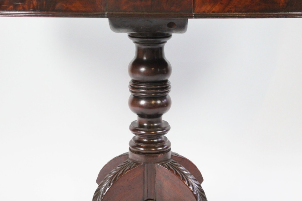 An early nineteenth-century Regency mahogany tea table with a folded rounded top resting on a turned central column and four splayed legs with brass castors. View IX