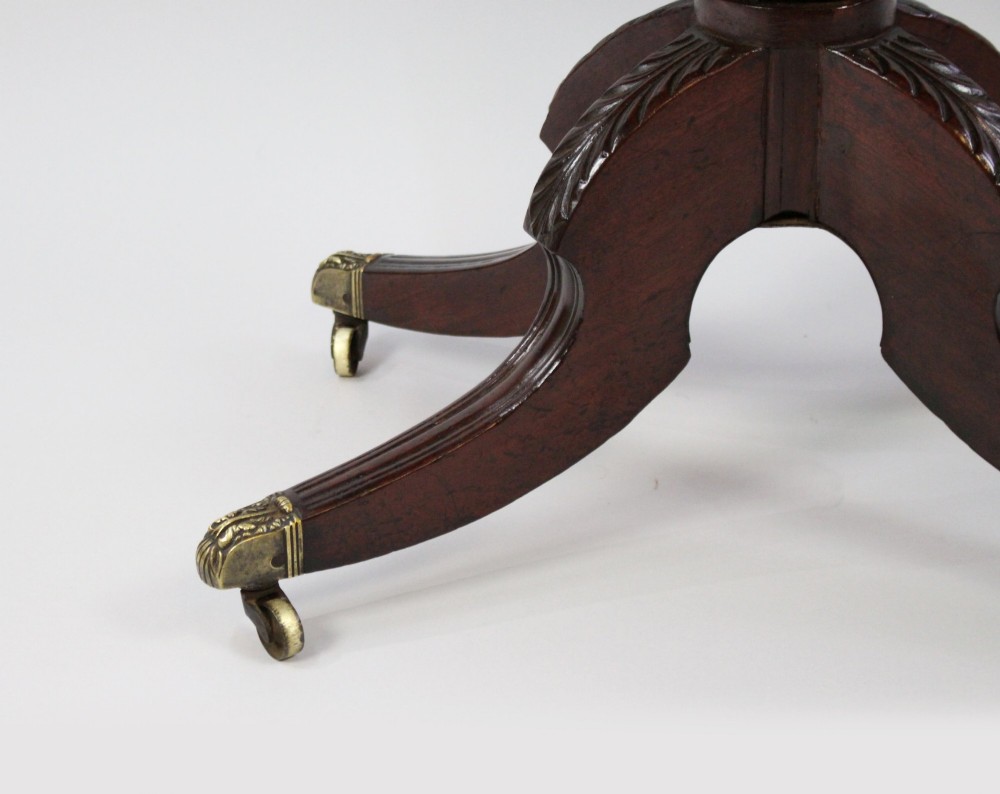 An early nineteenth-century Regency mahogany tea table with a folded rounded top resting on a turned central column and four splayed legs with brass castors. View XI