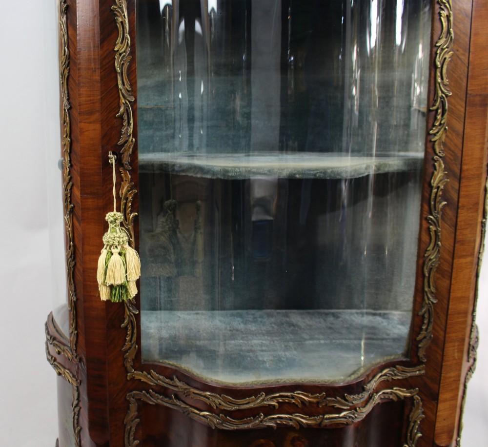 A nineteenth-century French serpentine display cabinet featuring curved glass panels, gilt bronze mounts, and hand-painted Vernis Martin panels on the lower section. View V