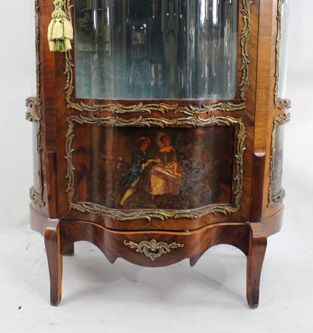 A nineteenth-century French serpentine display cabinet featuring curved glass panels, gilt bronze mounts, and hand-painted Vernis Martin panels on the lower section. View VI