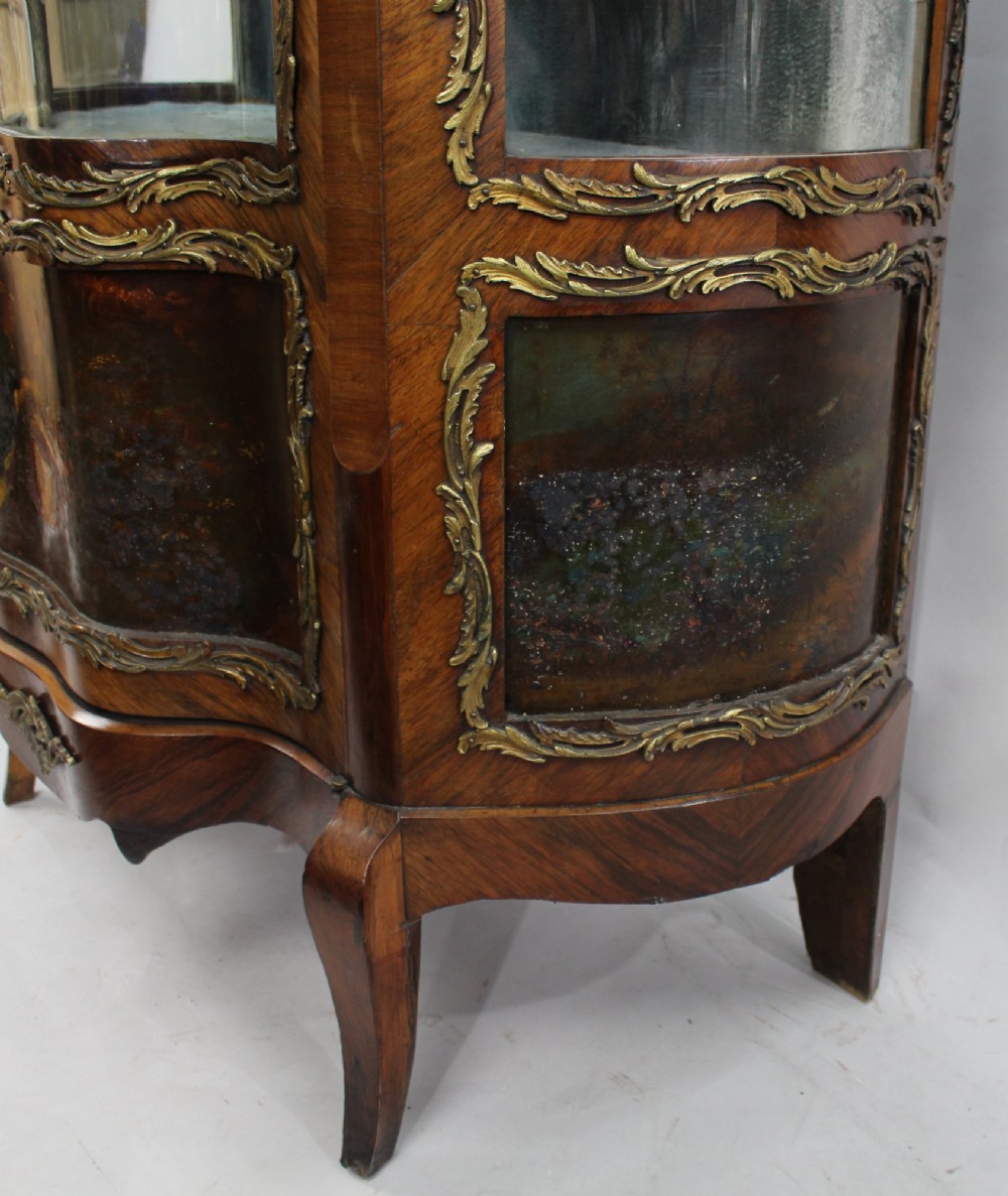 A nineteenth-century French serpentine display cabinet featuring curved glass panels, gilt bronze mounts, and hand-painted Vernis Martin panels on the lower section. View XI