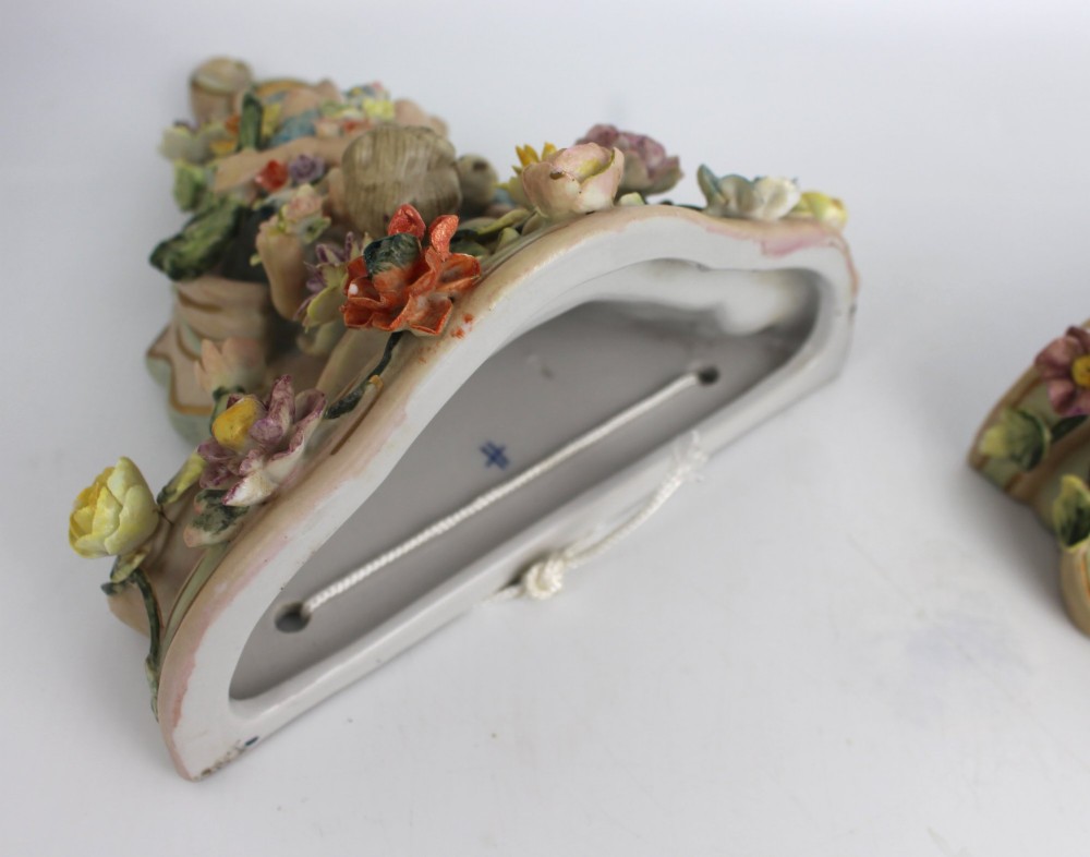 A pair of Rococo Revival porcelain wall corbels decorated with sculpted cherubs, elaborate scrollwork, and colourful encrusted flowers with gilt accents. View VII