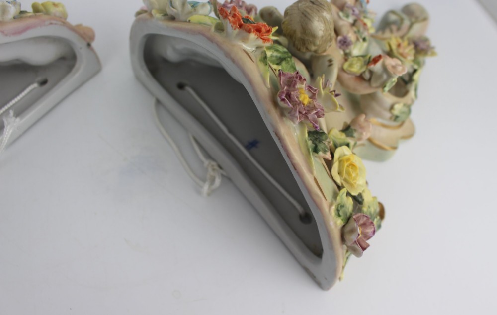 A pair of Rococo Revival porcelain wall corbels decorated with sculpted cherubs, elaborate scrollwork, and colourful encrusted flowers with gilt accents. View IX