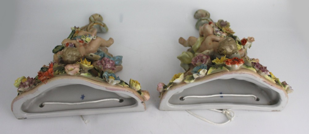 A pair of Rococo Revival porcelain wall corbels decorated with sculpted cherubs, elaborate scrollwork, and colourful encrusted flowers with gilt accents. View XI