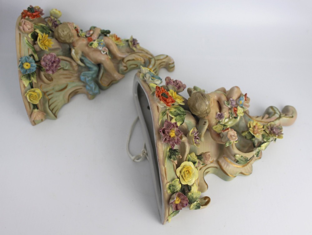A pair of Rococo Revival porcelain wall corbels decorated with sculpted cherubs, elaborate scrollwork, and colourful encrusted flowers with gilt accents. View XII