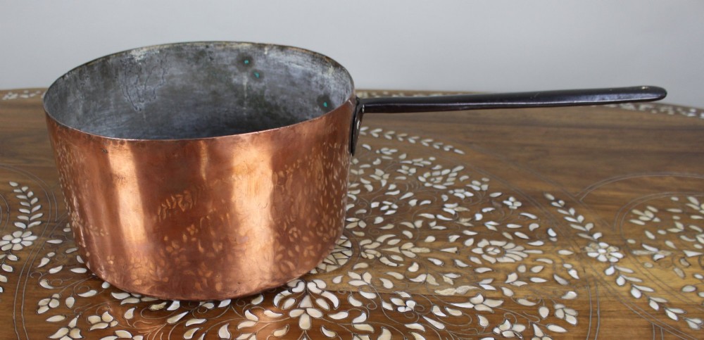 A large antique Georgian copper saucepan featuring a straight cylindrical body and a long wrought iron handle fastened with metal rivets. View II