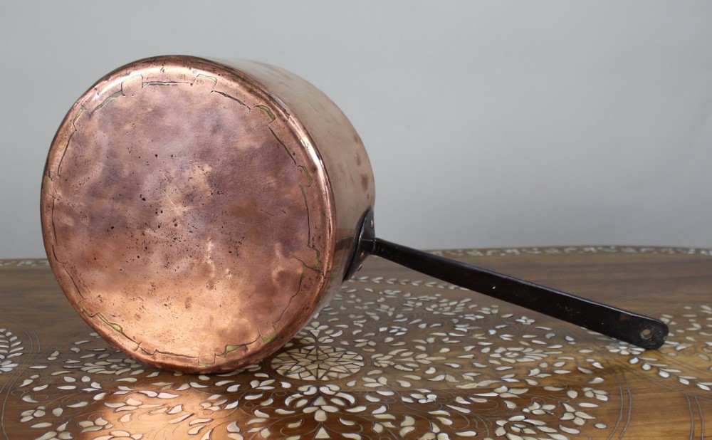 A large antique Georgian copper saucepan featuring a straight cylindrical body and a long wrought iron handle fastened with metal rivets. View IV