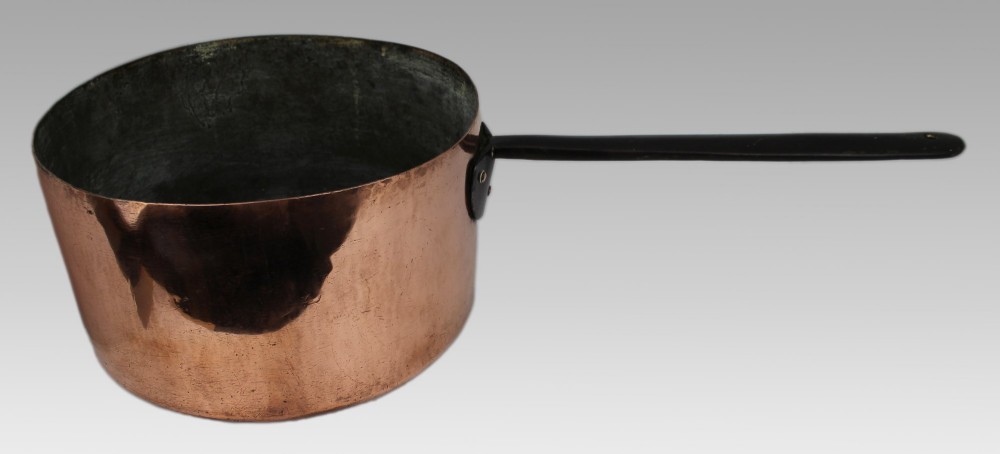 A large antique Georgian copper saucepan featuring a straight cylindrical body and a long wrought iron handle fastened with metal rivets. View VII